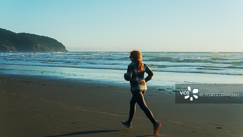 在日落时分俄勒冈海滩上跑步的女人图片素材