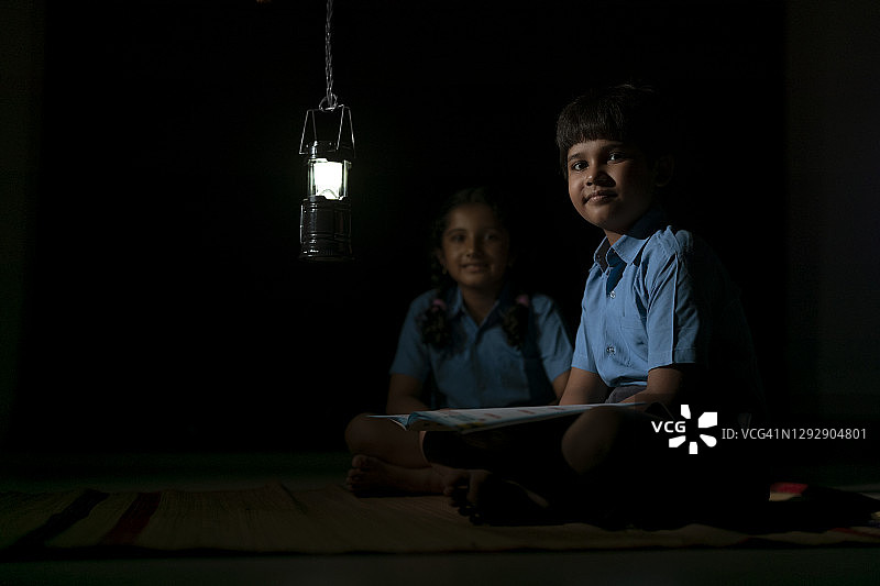 一个农村男孩和女孩在夜里学习，对着镜头微笑图片素材