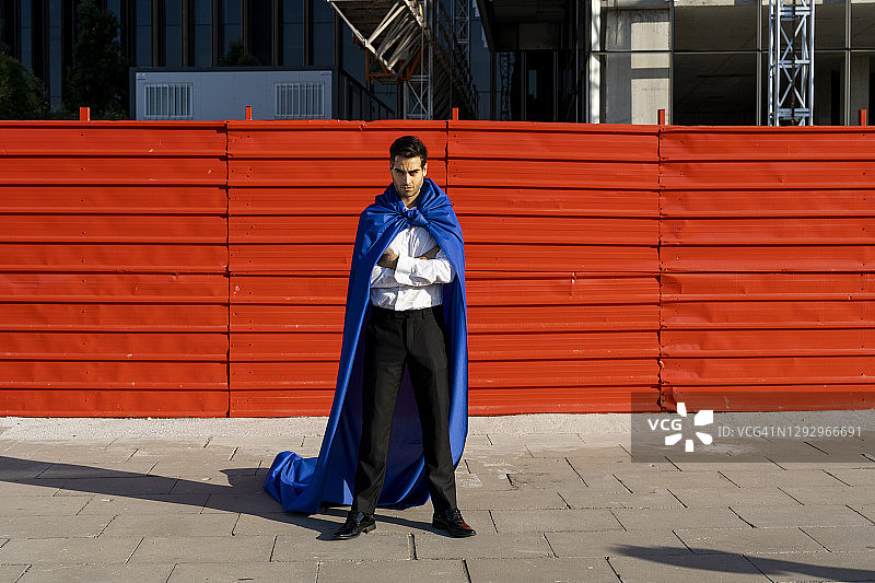 自信的商人穿着超级英雄斗篷在城市里图片素材
