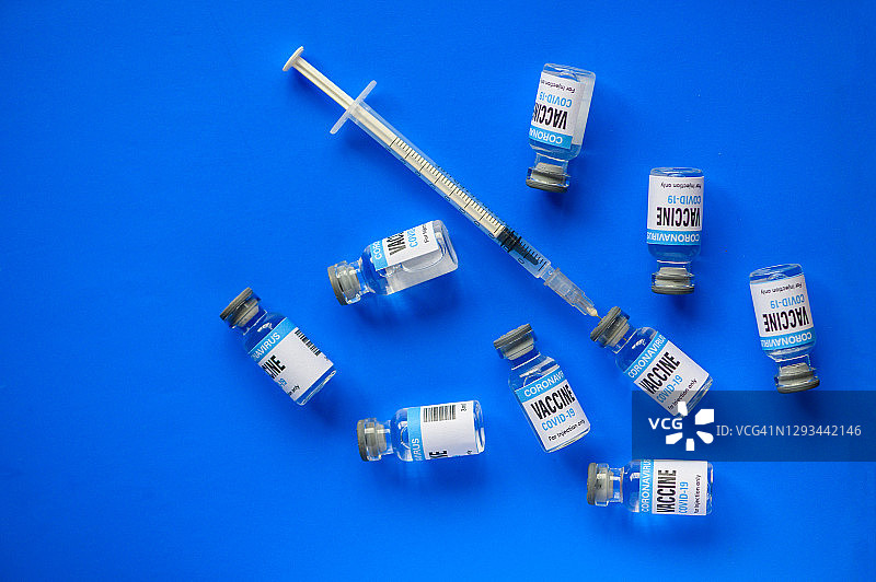 冠状病毒疫苗:注射器和小瓶，蓝色背景图片素材