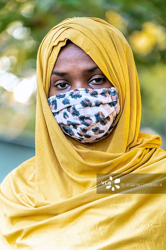 年轻的黑人穆斯林妇女戴着防护面罩看着镜头图片素材