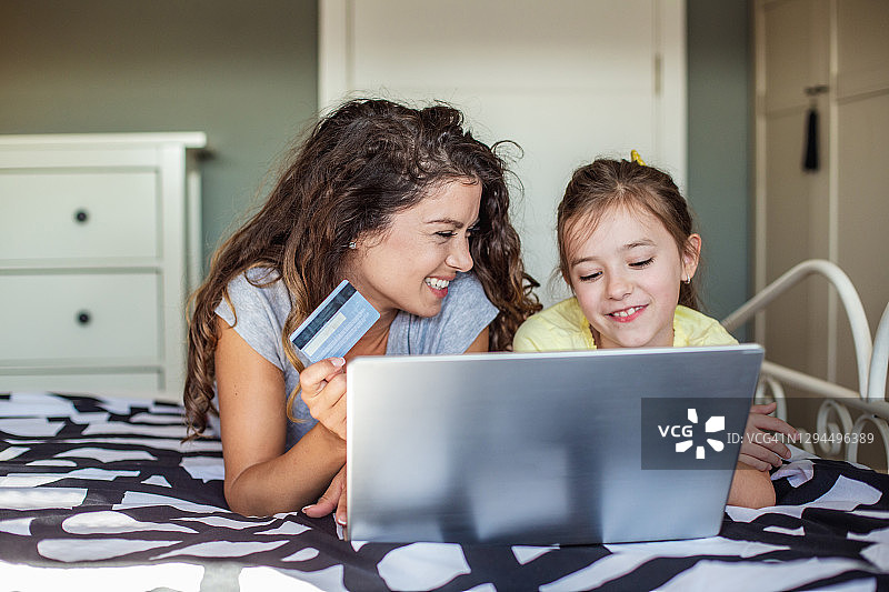 母亲和女儿在家里使用笔记本电脑进行网上购物图片素材