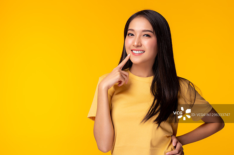肖像年轻的亚洲女人微笑美丽的女孩穿着黄色的T恤与黄色的背景拷贝空间在工作室漂亮的亚洲女性得到自信漂亮的女性有长头发可爱的女士得到快乐图片素材