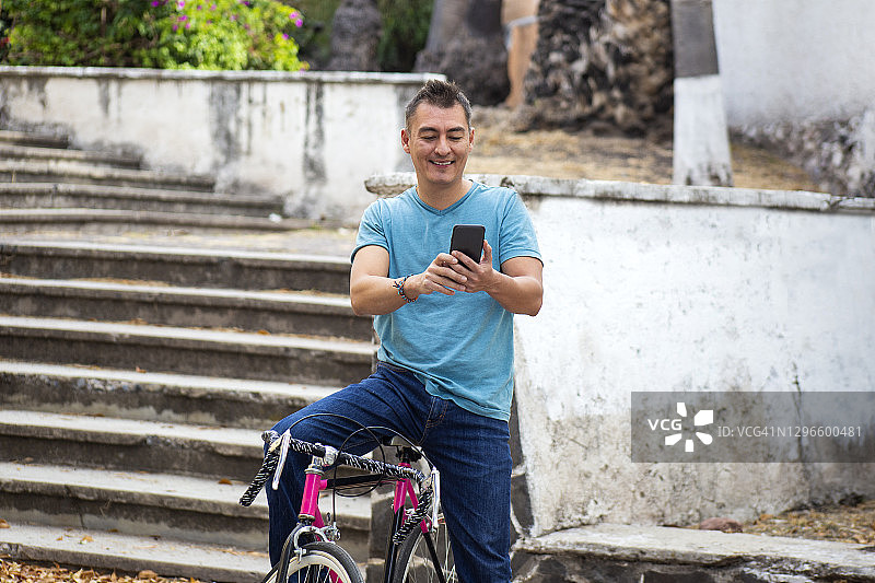一个男人站在自行车上，看着他的手机图片素材