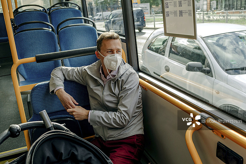 2019冠状病毒病(COVID-19)期间，中年男子从公交车上往窗外看图片素材