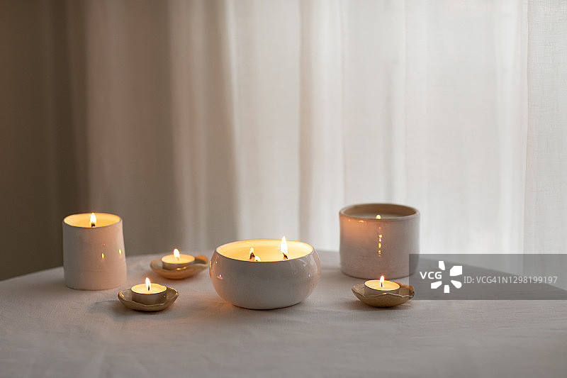 亚麻桌布上的陶瓷碗里放着香薰蜡烛。图片素材