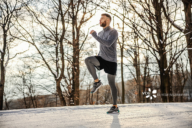 健硕的运动员在多雪的冬日在大自然中奔跑。寒冷的天气，冬季健身，有氧运动图片素材