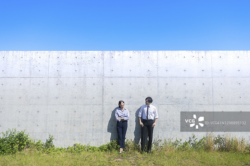 一男一女站在水泥墙前图片素材