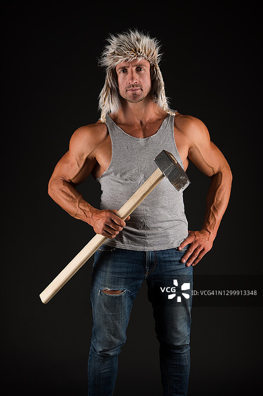 运动工人持锤工具在强壮的手臂二头肌三头肌在休闲穿黑色背景，矿工图片素材