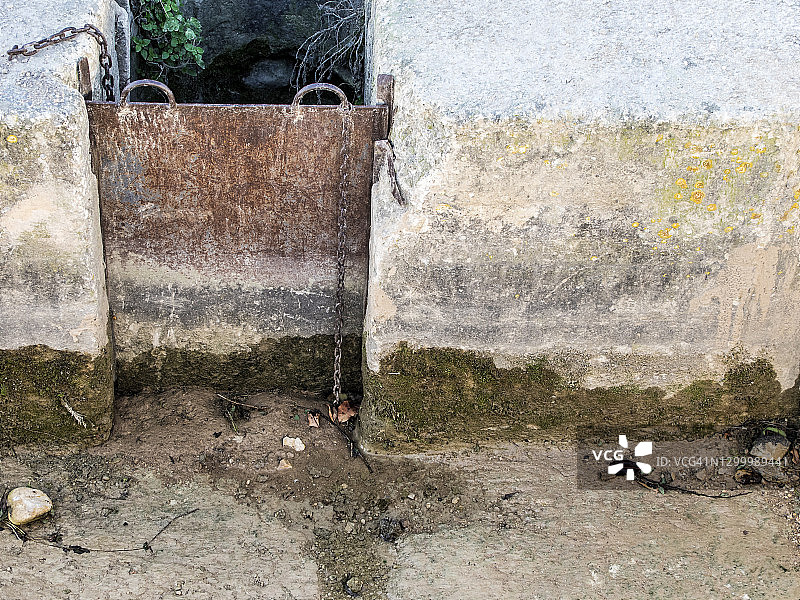 灌溉渠用清水浇灌一片菜地，铁栏门。图片素材