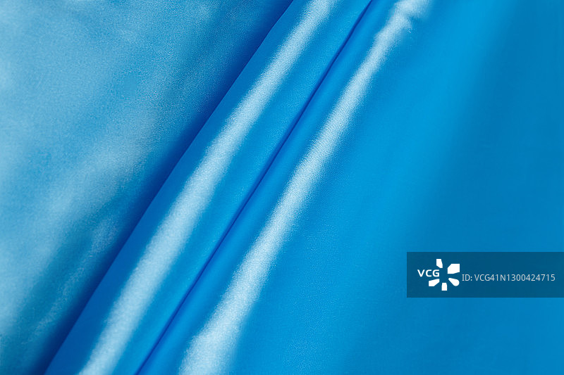 彩色的蓝色纺织缎子织物折叠和波浪与亮点和纹理图片素材