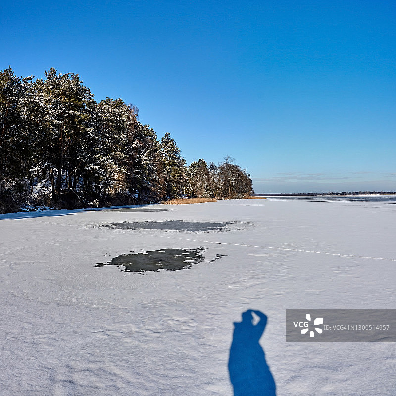 摄影师在冬天拍摄冰冻河流的剪影。图片素材