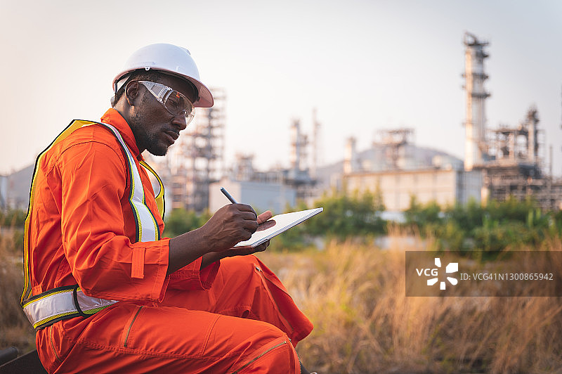 非洲种族安全工程师在石油和天然气行业的户外平板电脑工作的肖像图片素材