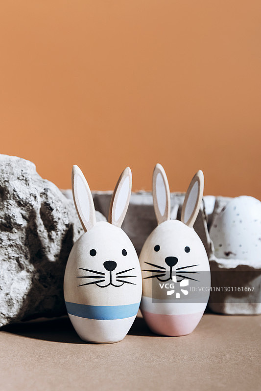复活节彩蛋托盘的背景上有粉色和蓝色条纹的木制兔子图片素材