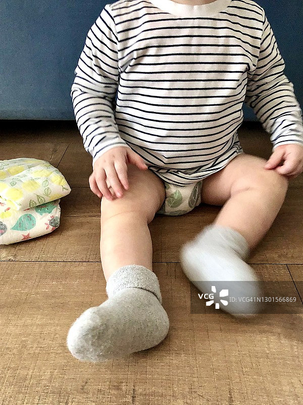 男婴穿着婴儿尿布坐在地板上，选择性聚焦图片素材
