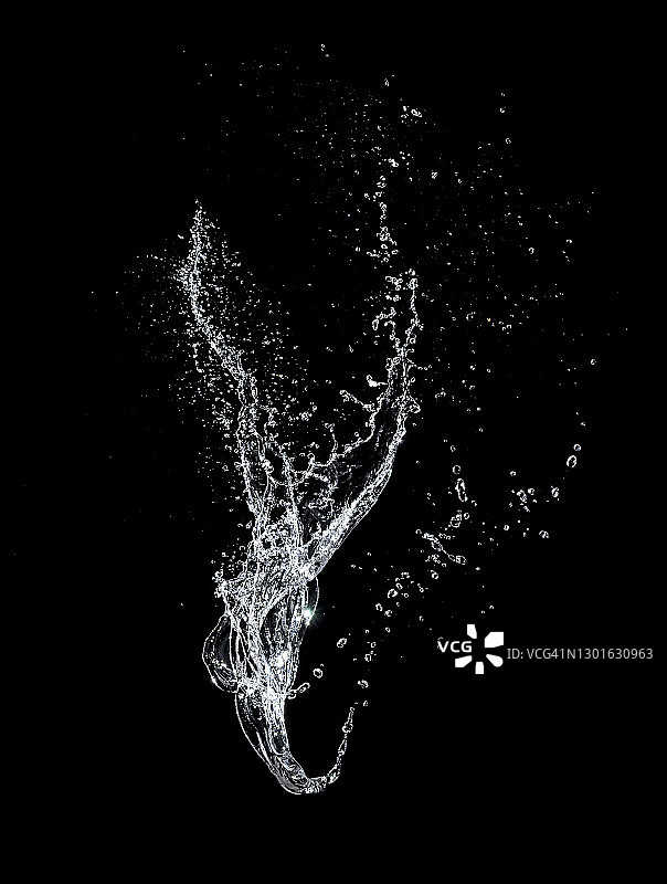 飞溅、喷射和水滴在运动中悬浮在空中的黑色背景。图片素材