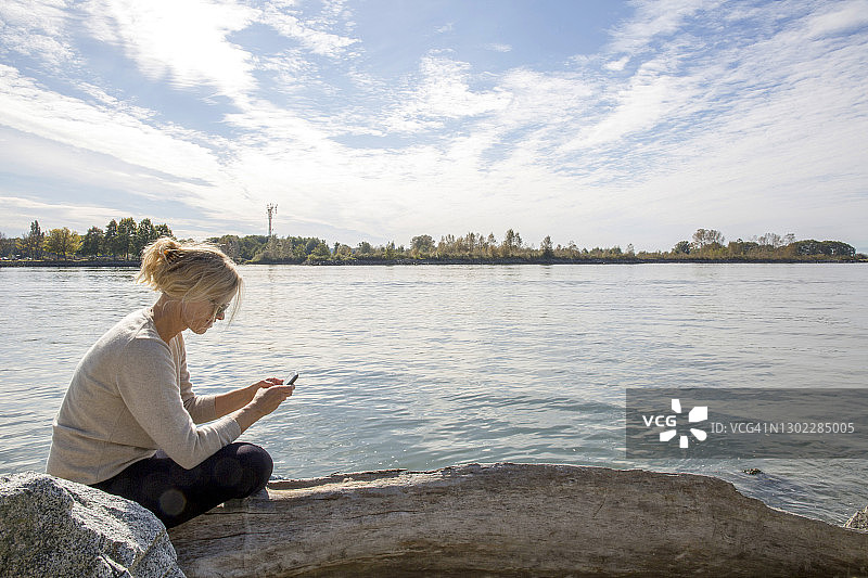 女子在河岸上使用智能手机图片素材