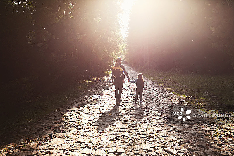 一个男人带着女儿走在森林里的岩石路上图片素材