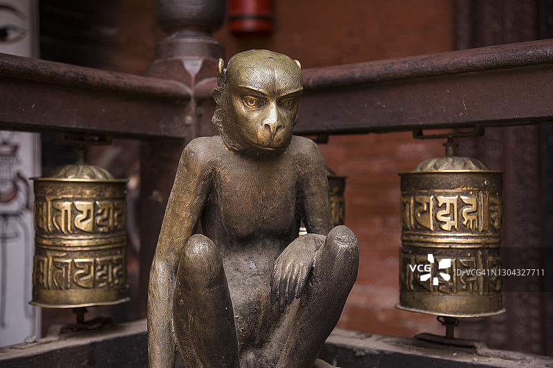 尼泊尔加德满都帕坦拉利特普尔的Hiranya Varna Mahavihar或Kwa baal佛教寺庙的主庭院中，铜猴子雕塑和佛教转经轮的两边。图片素材