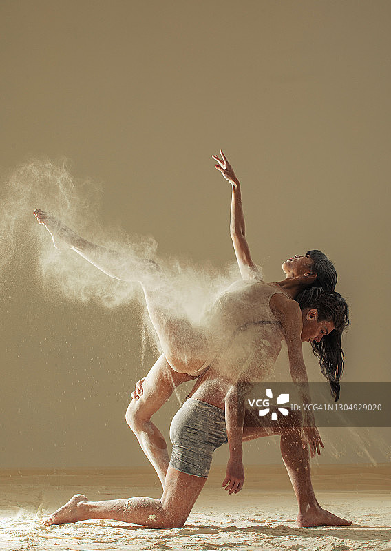 两名芭蕾舞者在空中白面云的背景下表演舞蹈。图片素材