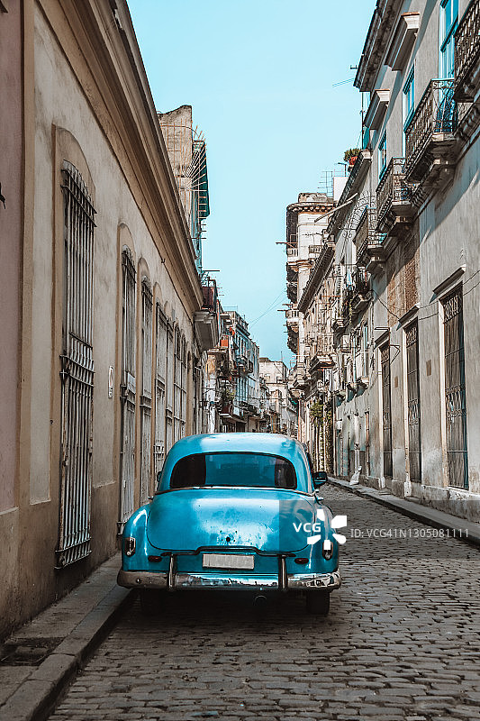 古巴哈瓦那，一辆停在鹅卵石街上的蓝色汽车图片素材