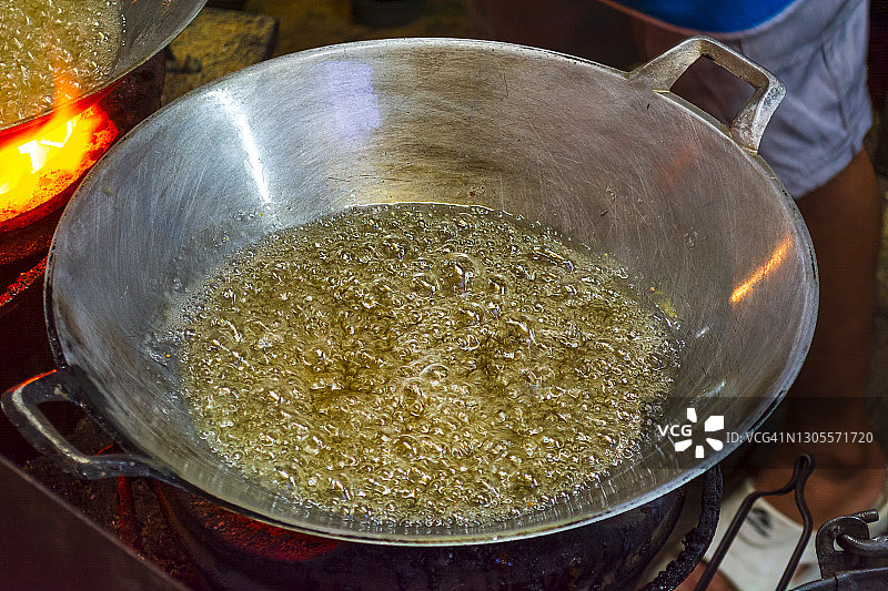 金色纹理的近距离闪光黄热油沸腾和创造泡沫在一个银锅。图片素材