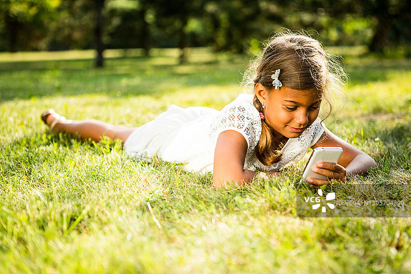 草地上拿着智能手机的女孩图片素材