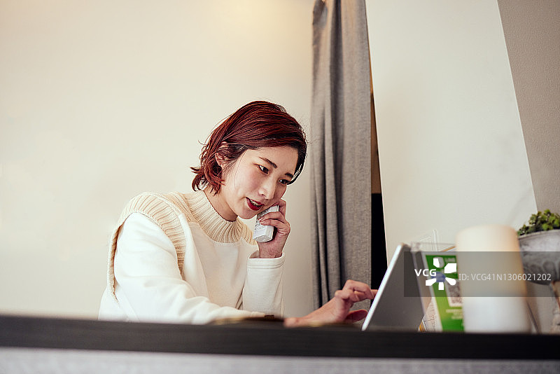 一个微笑的女人使用手机或平板电脑在一个美容沙龙的前台工作的肖像图片素材