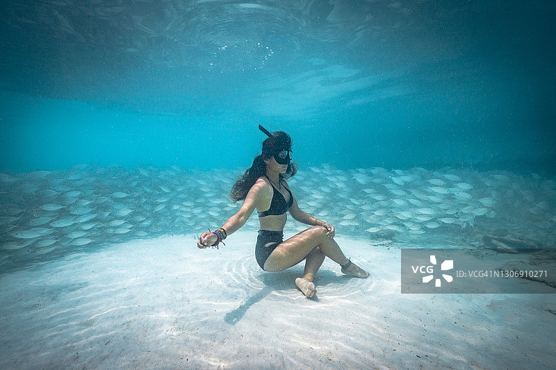 一名自由潜水者在鱼群附近摆姿势的水下镜头图片素材