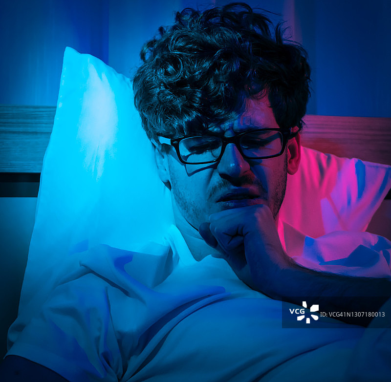 失眠症失眠的人有一个问题，睡到很晚，闹钟告诉深夜他的床上。图片素材