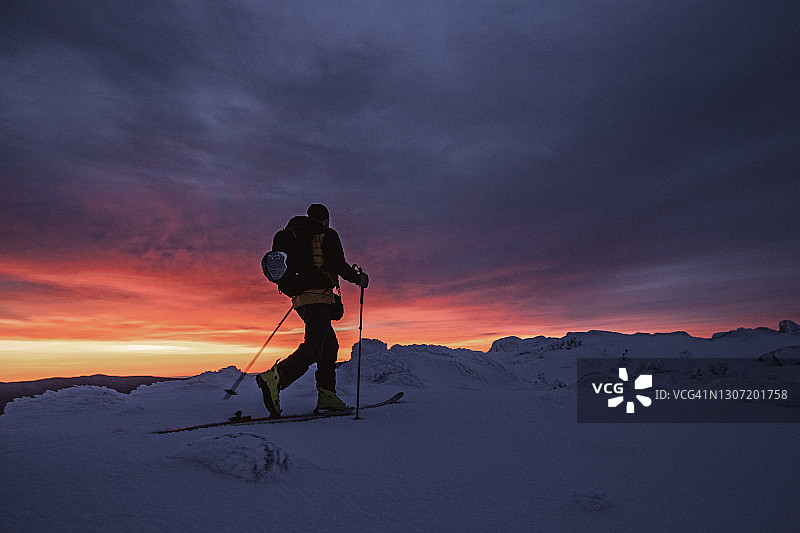 在鲜艳的红色日出，美国新罕布什尔州华盛顿山的野外滑雪者图片素材
