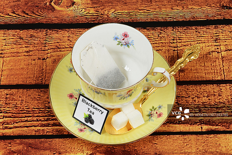 采购产品茶杯和茶碟，茶包，勺子和方糖在木头桌子上图片素材