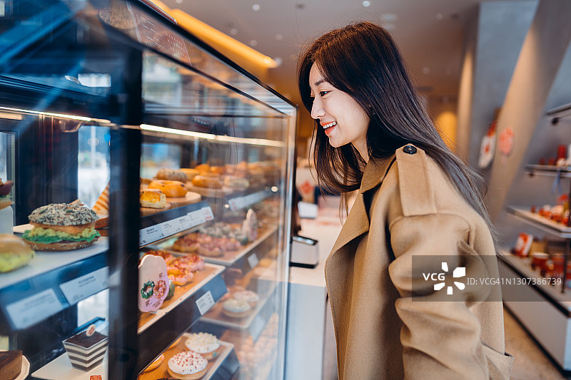 亚洲年轻女子在咖啡店选择糖果。图片素材