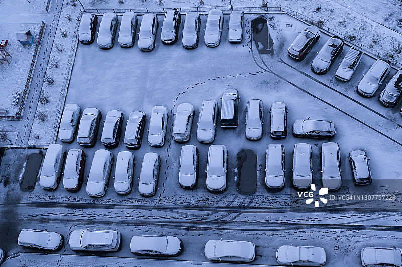 房子附近街道停车场上被雪覆盖的汽车。图片素材