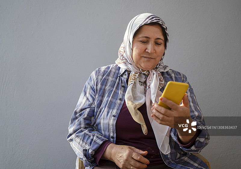成熟的穆斯林妇女戴着头巾使用智能手机图片素材