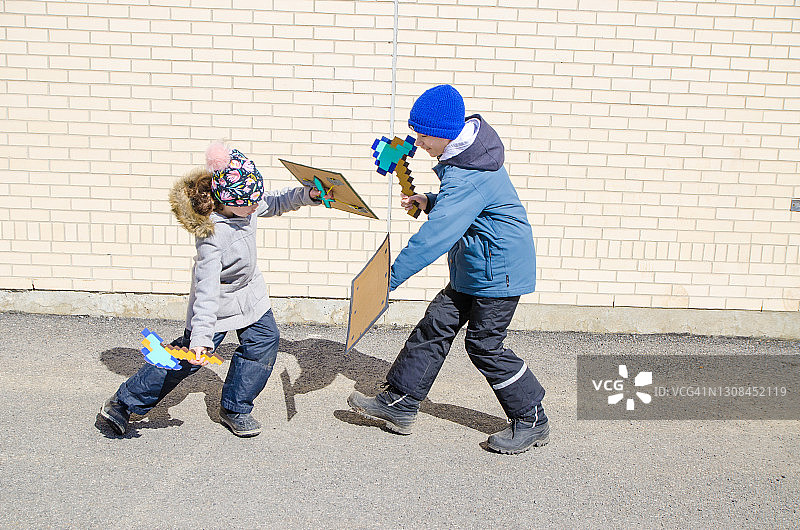 两个孩子用纸板斧和盾牌打架图片素材