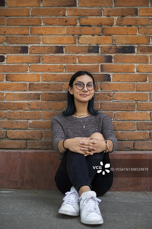 一位年轻的西班牙妇女微笑着坐在墨西哥城的人行道上图片素材
