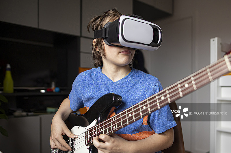 男孩一边弹吉他一边看虚拟现实图片素材