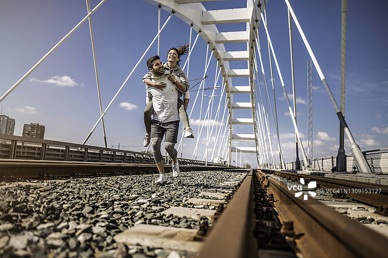 快乐的运动年轻夫妇在铁轨上奔跑。图片素材
