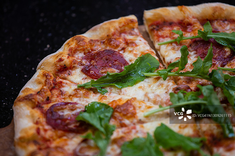 近距离的美味切片新鲜披萨服务在黑暗的桌子图片素材