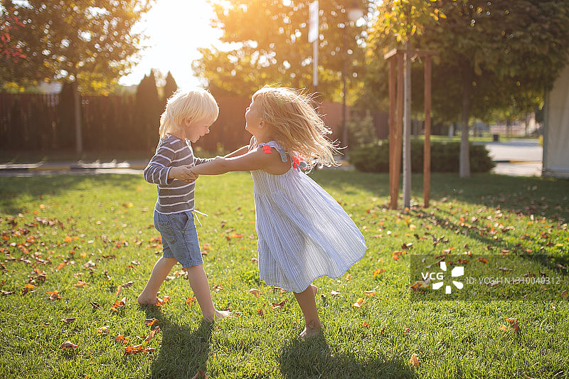 女孩和男孩在公园里玩耍，旋转，欢笑的夏天图片素材