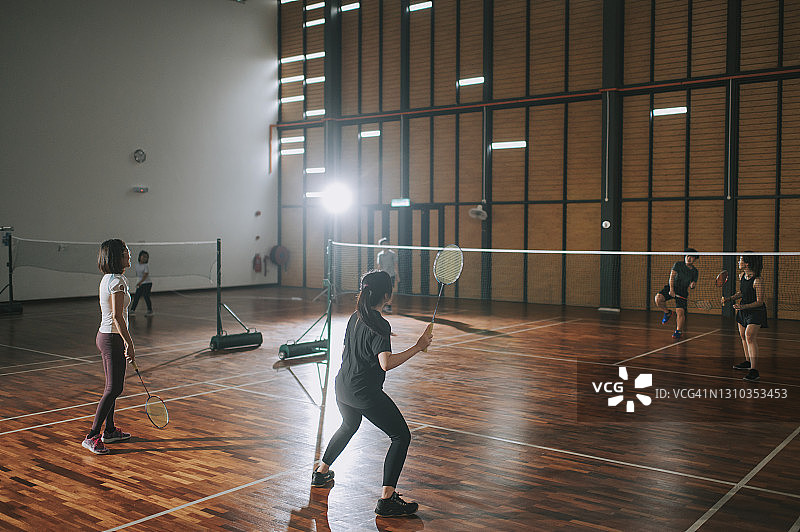 亚洲华人女子羽毛球运动员在羽毛球场上比赛图片素材
