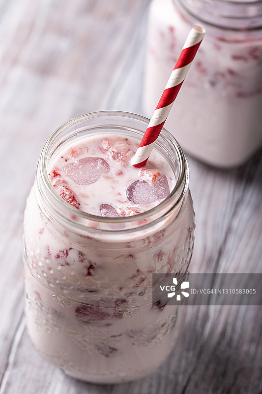 高角度的草莓奶昔在玻璃罐上的白色木制乡村背景，健康的食物概念为早餐或午餐图片素材