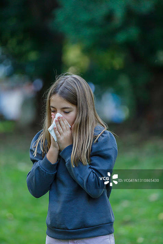 患有季节性过敏症的女孩用纸巾擤鼻子。图片素材