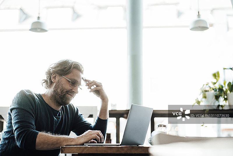 男性企业家在咖啡馆使用笔记本电脑图片素材