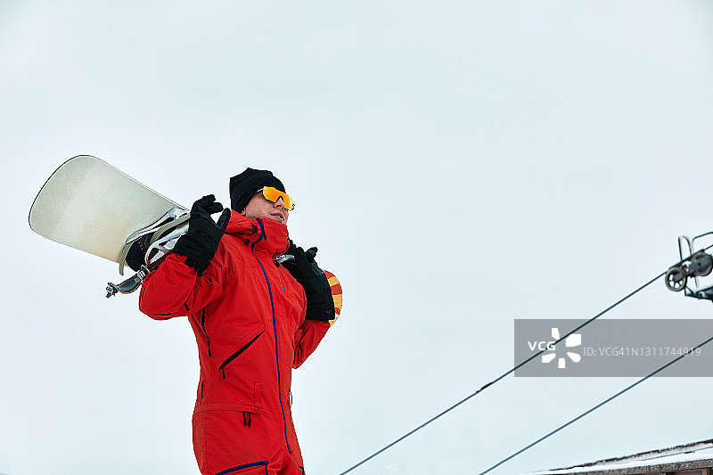 穿着红色衣服的男性滑雪板行走在雪山滑雪板，滑雪和滑雪板的概念图片素材