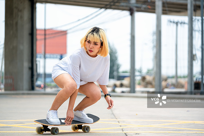 年轻女子在停车场玩冲浪滑板。图片素材