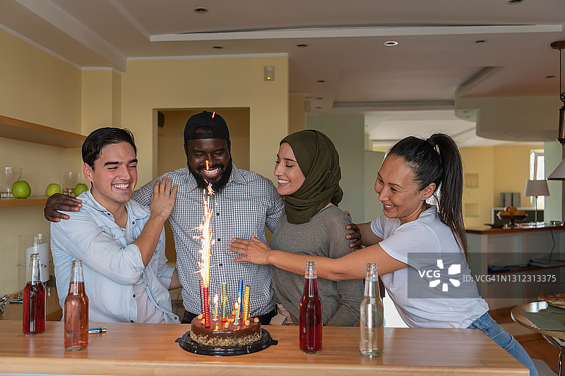 一群年轻的多文化朋友在一起度过美好的时光，而他们的非洲朋友正在举行生日派对。图片素材