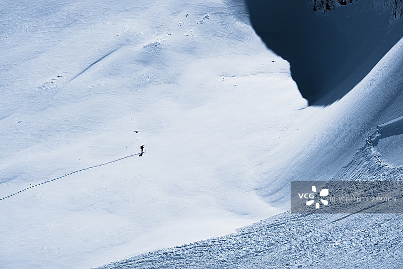 鸟瞰图的一个偏远的滑雪者打破踪迹横跨一个大的冰雪覆盖的冰川在海岸山脉。图片素材
