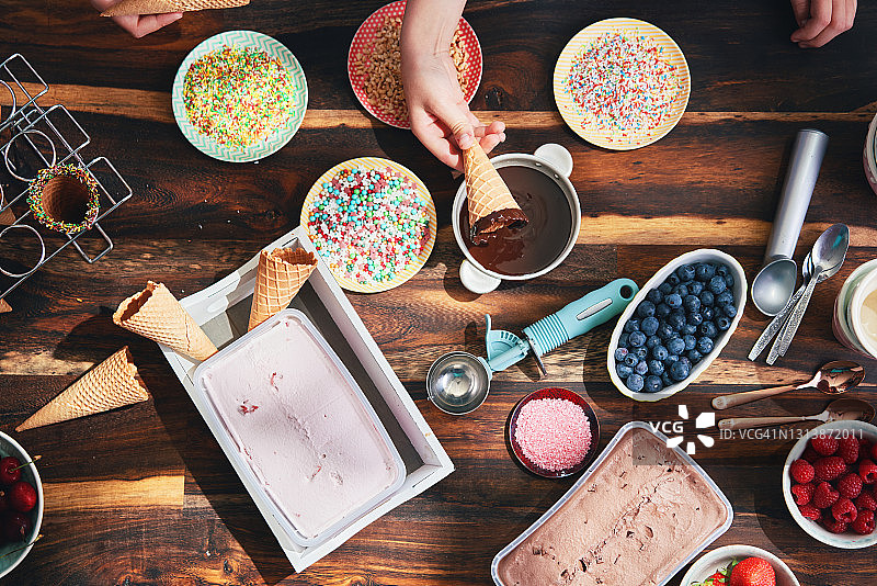 准备甜筒冰淇淋的小女孩，有各种浇头、水果和糖果图片素材